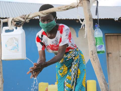 A masked girl washing her hands